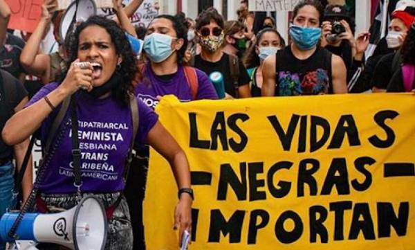A group of protesters carry a banner that reads "Las vidas negras importan"