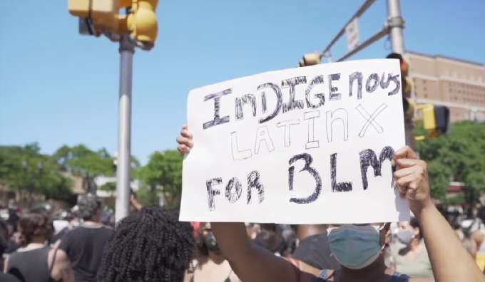 A person holds a sign supporting Black live matters and the Latin community