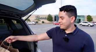 Un joven latino coloca sus compras en el maletero de un carro