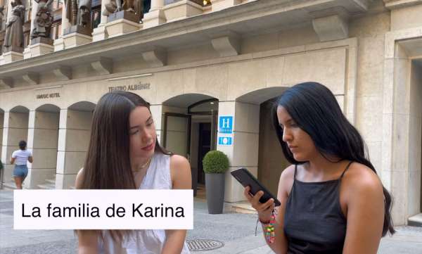 Two Spanish girls on the street. One of them has her cellphone on her hand. There's a title that reads: "La familia de Karina"